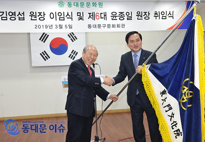 김영섭 전 문화원장왼쪽이 윤종일 신임 문화원장에게 동대문문화원기를 인계하고 있다사진  동대문 이슈 